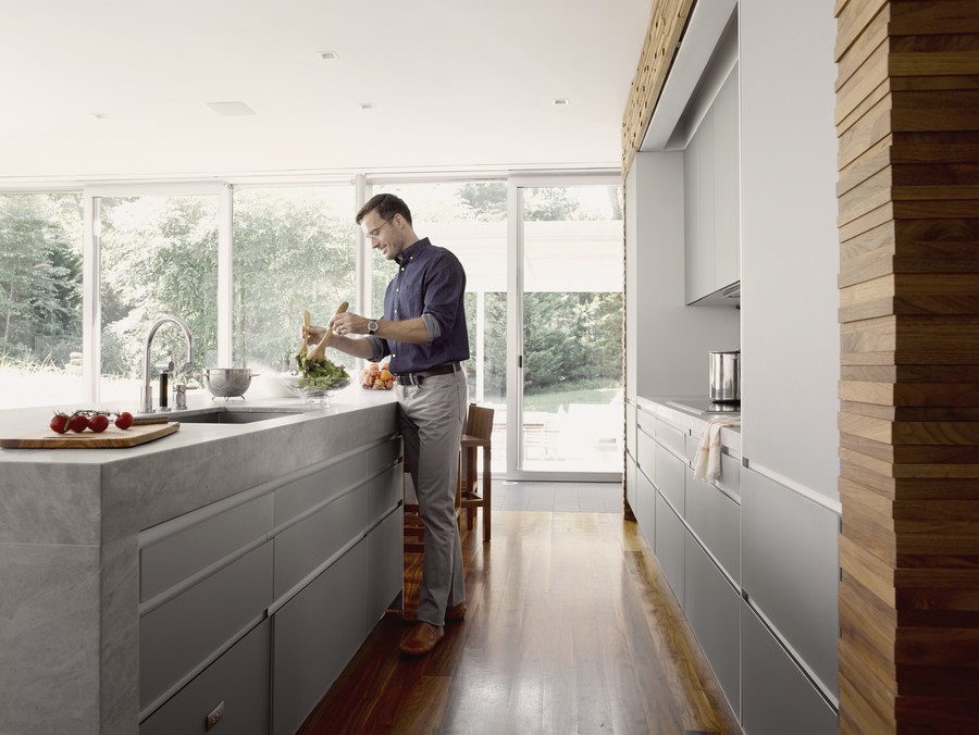 man standing at a kitchen island preparing a salad in a Savant smart home.