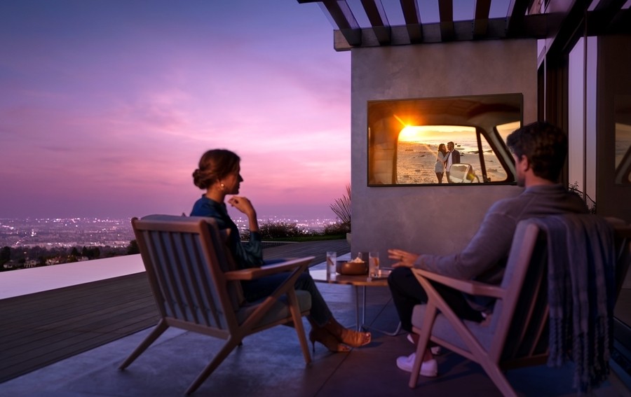 Samsung Terrace TV installed under a pergola awning on a patio overlooking a cityscape.