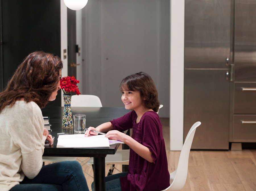 a parent and child work on homework at a kitchen table