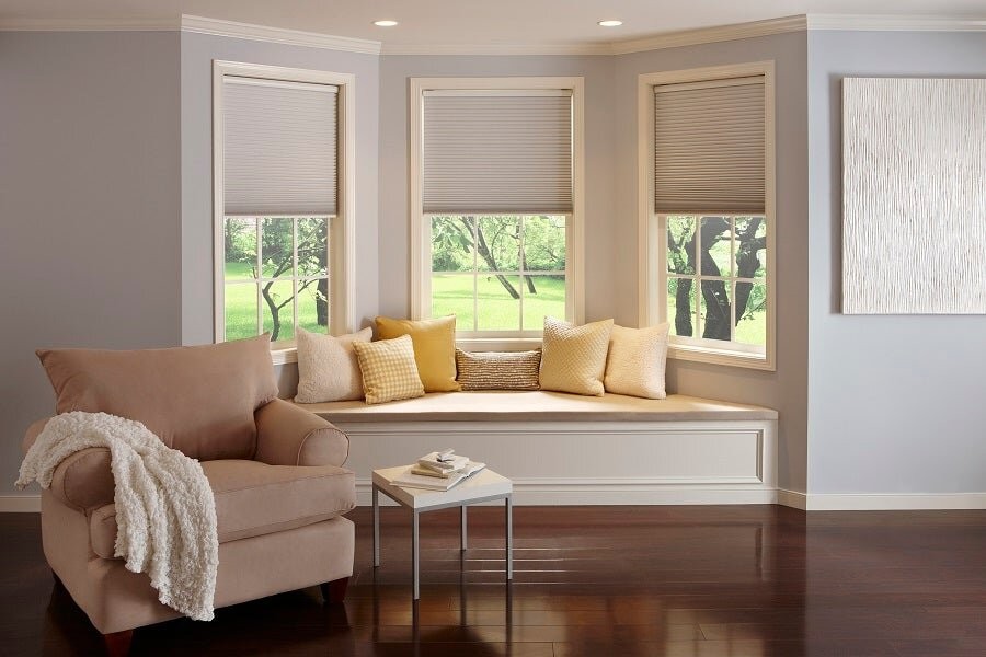 A family room area with a couch and windows behind it, featuring motorized blinds lowered halfway.